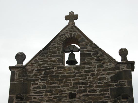 Le clocher de Saint Etienne, encadré par deux stèles discoïdales.