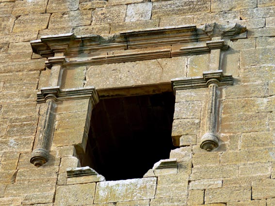 Une fenêtre flanquée de pilastres qui soutiennent un entablement mouluré.