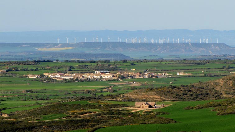 Le village d'Apiès, avec une forêt d'éoliennes en arrière-plan.
