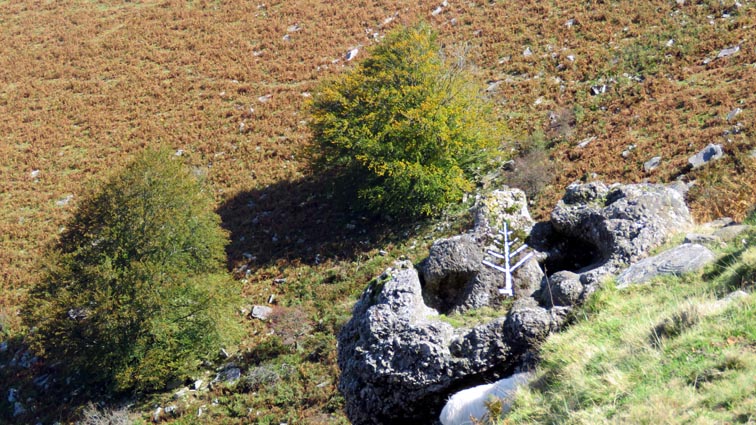 Une croix massive gravée dans un rocher, ornée d'un arbre de vie en mosaïque.